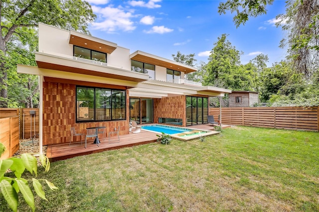 back of property with a lawn, a balcony, and a pool side deck