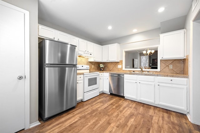 kitchen with decorative backsplash, stainless steel appliances, an inviting chandelier, hardwood / wood-style floors, and white cabinetry