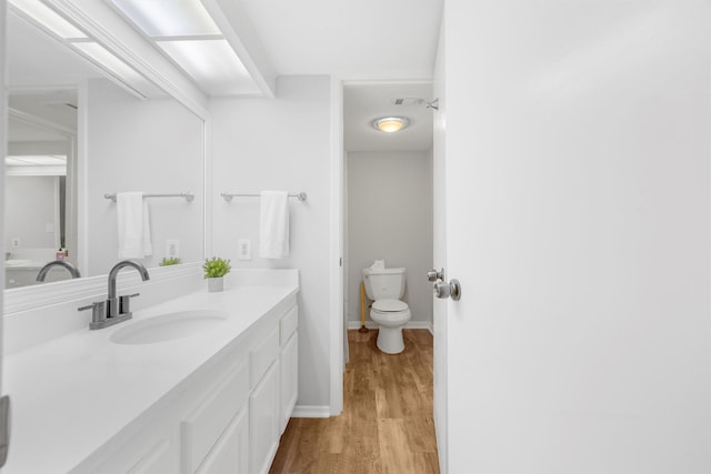 bathroom with hardwood / wood-style floors, vanity, and toilet