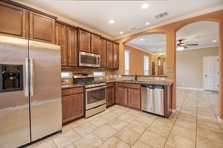 kitchen featuring appliances with stainless steel finishes, ceiling fan, ornamental molding, and sink