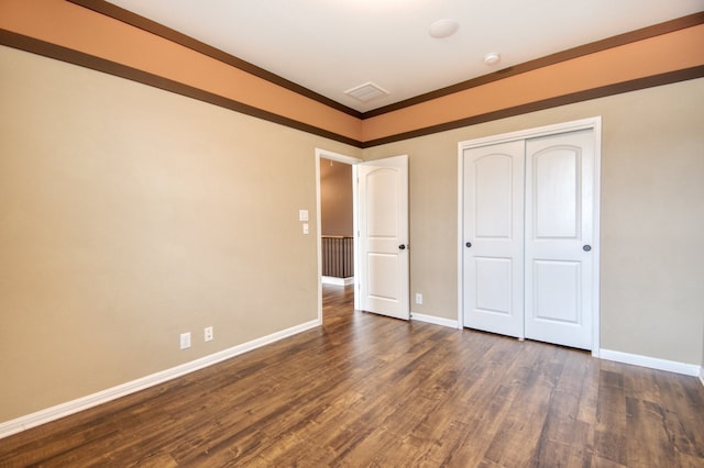 unfurnished bedroom with dark hardwood / wood-style flooring, a closet, and crown molding