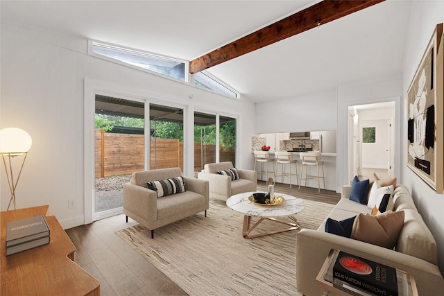 living room featuring lofted ceiling with beams, light hardwood / wood-style flooring, and a healthy amount of sunlight