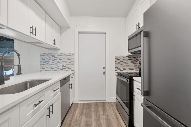 kitchen with backsplash, white cabinets, sink, crown molding, and stainless steel appliances