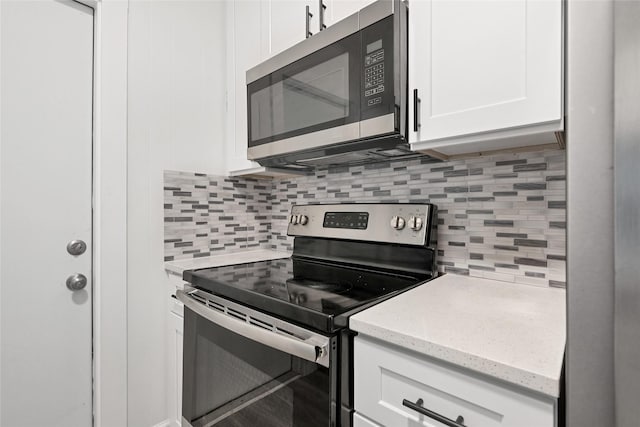 kitchen with white cabinets, light stone countertops, appliances with stainless steel finishes, and tasteful backsplash