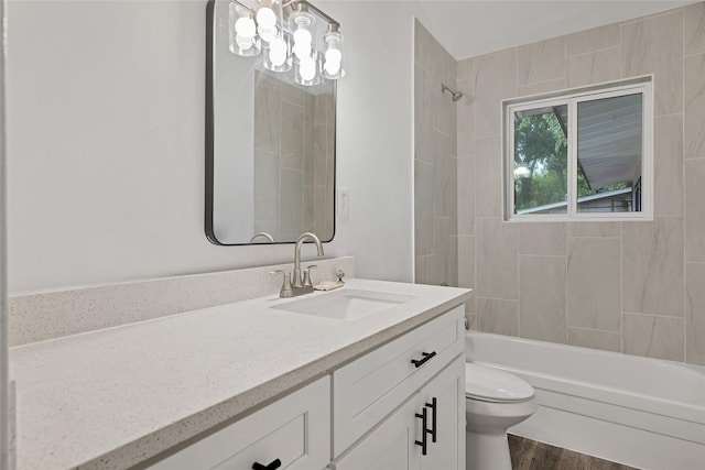 full bathroom featuring hardwood / wood-style floors, vanity, toilet, and tiled shower / bath combo