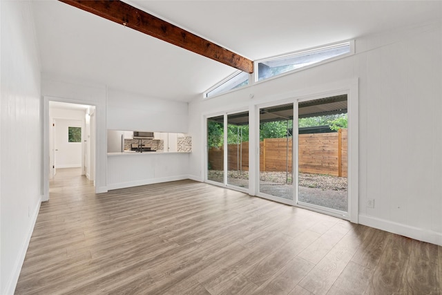 unfurnished living room featuring vaulted ceiling with beams and light hardwood / wood-style flooring