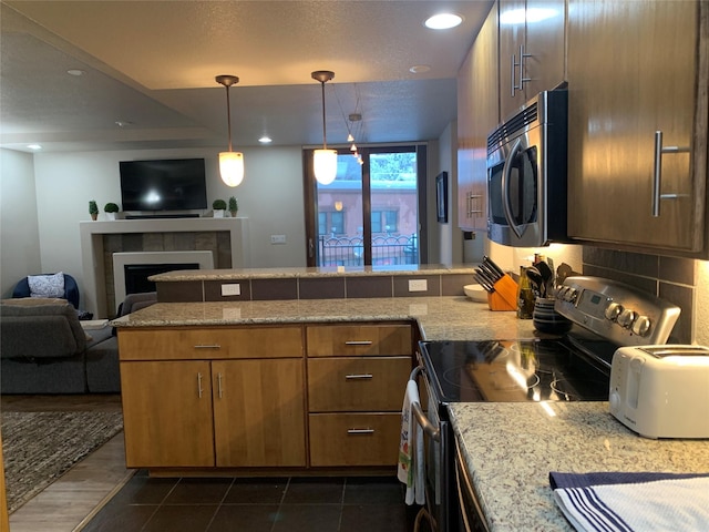 kitchen with a fireplace, kitchen peninsula, dark tile patterned floors, and electric stove