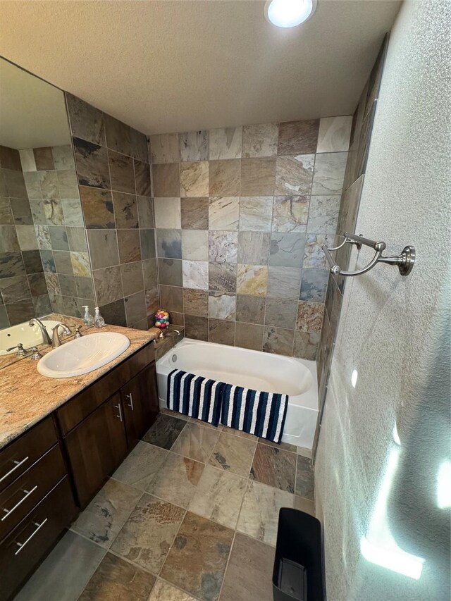 bathroom featuring vanity, a bath, a textured ceiling, and tile walls