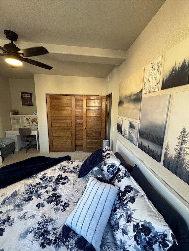 bedroom with beamed ceiling, ceiling fan, and a textured ceiling