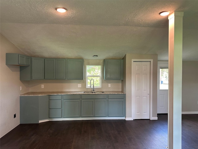 kitchen with a textured ceiling, lofted ceiling, dark wood-type flooring, and sink