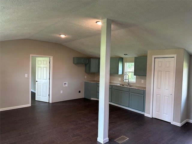 kitchen featuring a textured ceiling, dark hardwood / wood-style flooring, vaulted ceiling, and sink