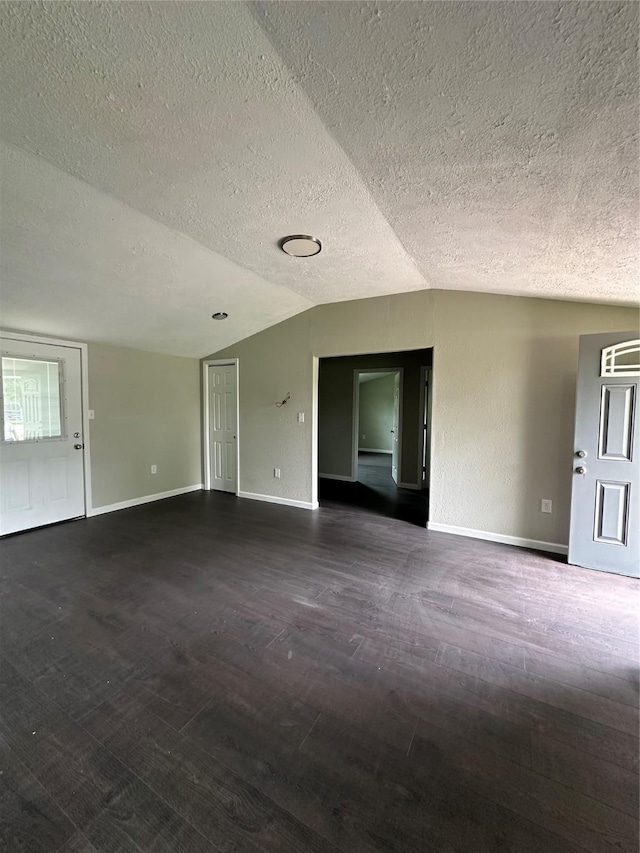 unfurnished room featuring dark hardwood / wood-style flooring, a textured ceiling, and vaulted ceiling