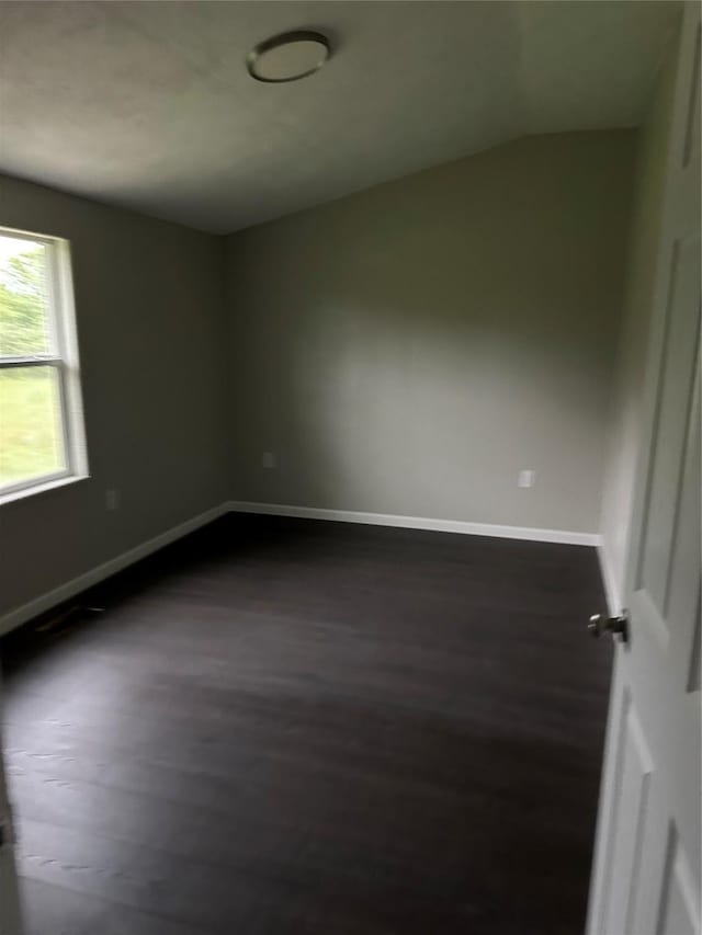 unfurnished room featuring dark wood-type flooring and lofted ceiling