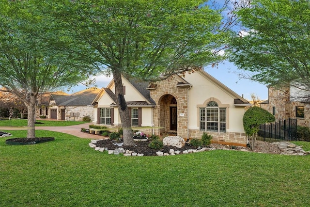 view of front of home with stone siding, a front yard, fence, and stucco siding