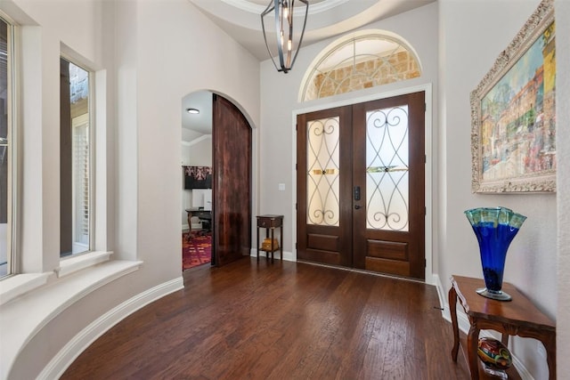 entryway with wood-type flooring, baseboards, arched walkways, and french doors