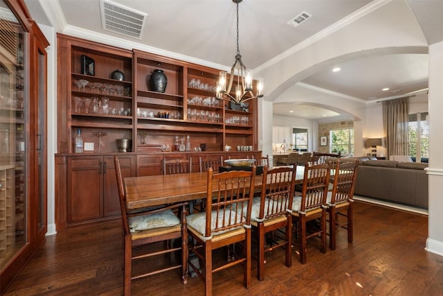 dining area featuring arched walkways, dark wood finished floors, visible vents, and crown molding