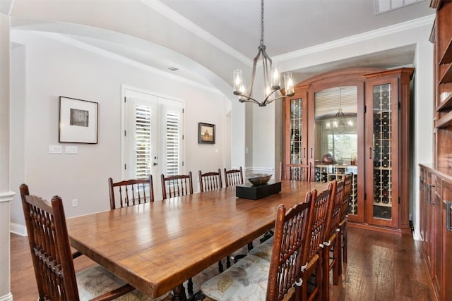 dining room featuring arched walkways, dark wood finished floors, ornamental molding, french doors, and a chandelier