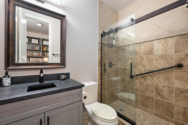 bathroom with toilet, a shower stall, and vanity