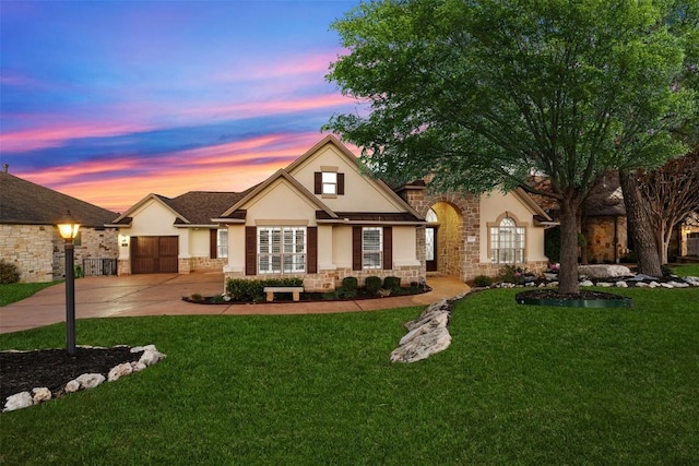 view of front facade featuring a garage, driveway, a lawn, and stucco siding