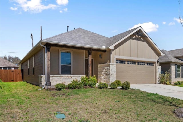 view of front of home featuring a front yard, an attached garage, stone siding, and concrete driveway