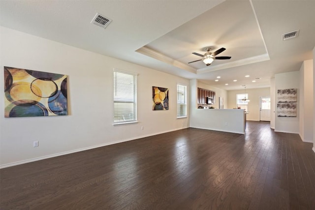 unfurnished living room with ceiling fan, crown molding, dark hardwood / wood-style flooring, and a tray ceiling