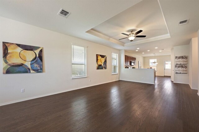1420 Cliffbrake Way, Georgetown, TX 78626 - unfurnished living room featuring a tray ceiling, plenty of natural light, ornamental molding, ceiling fan, and dark wood-style flooring