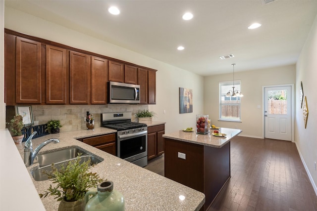 kitchen with visible vents, a kitchen island, a sink, decorative backsplash, and appliances with stainless steel finishes