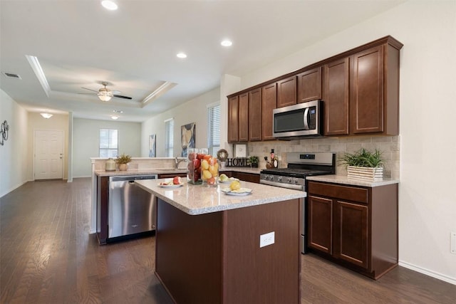 1420 Cliffbrake Way, Georgetown, TX 78626 - kitchen featuring stainless steel appliances, a peninsula, dark wood-type flooring, backsplash, and a kitchen island