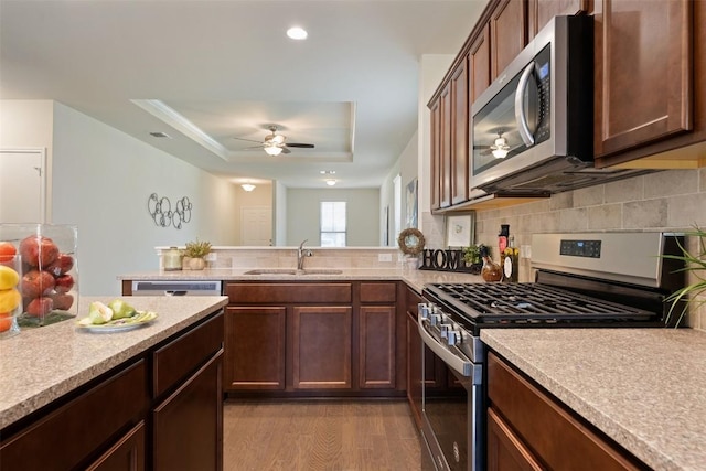 1420 Cliffbrake Way, Georgetown, TX 78626 - kitchen with appliances with stainless steel finishes, light countertops, a tray ceiling, ceiling fan, and wood finished floors