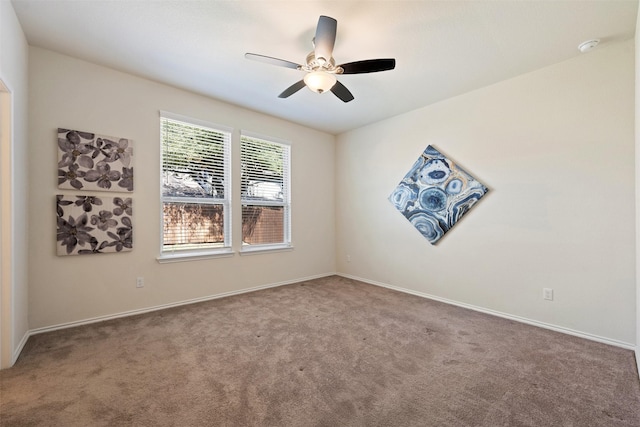 carpeted spare room with a ceiling fan and baseboards