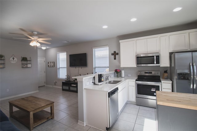 kitchen featuring kitchen peninsula, white cabinetry, light tile patterned flooring, and stainless steel appliances