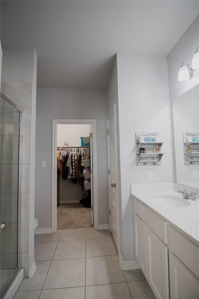 bathroom with toilet, tile patterned flooring, vanity, and walk in shower