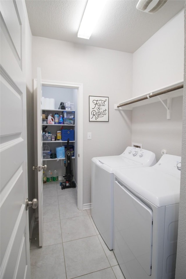 laundry room with washing machine and clothes dryer, light tile patterned floors, and a textured ceiling