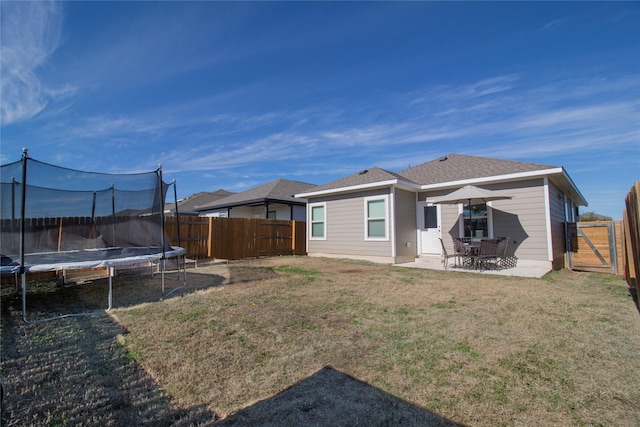 back of house with a yard, a patio, and a trampoline