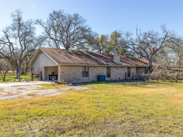 rear view of property with a lawn, central AC unit, and a carport