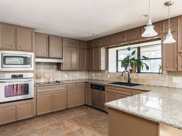 kitchen featuring kitchen peninsula, stainless steel appliances, sink, pendant lighting, and light tile patterned floors