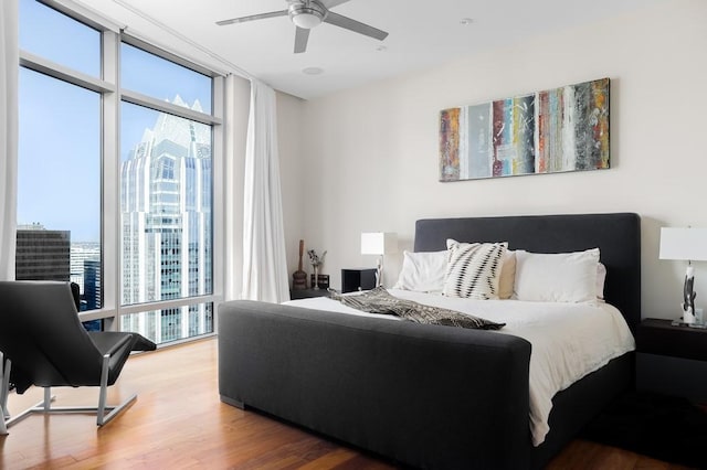 bedroom featuring hardwood / wood-style floors, expansive windows, and ceiling fan