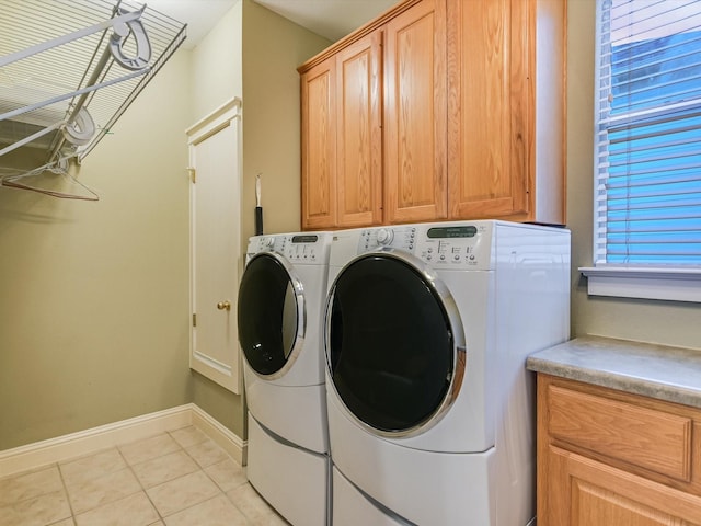 laundry area with washing machine and clothes dryer, light tile patterned flooring, and cabinets