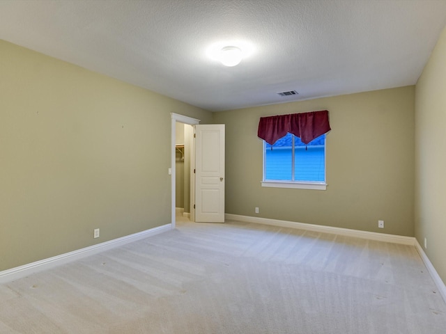 carpeted empty room featuring a textured ceiling