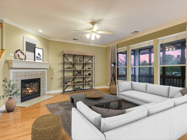 living room featuring hardwood / wood-style floors, ceiling fan, ornamental molding, and a fireplace