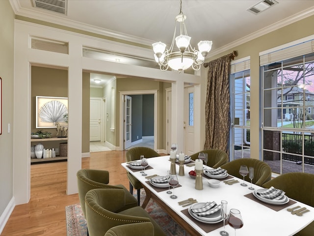 dining room with crown molding, light hardwood / wood-style flooring, and a chandelier