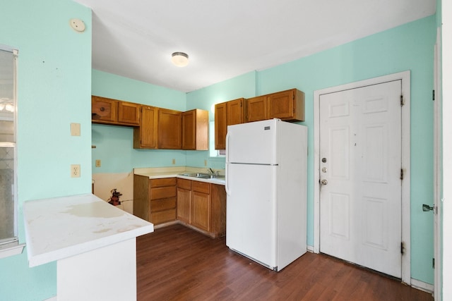 kitchen featuring white refrigerator, dark hardwood / wood-style flooring, kitchen peninsula, and sink