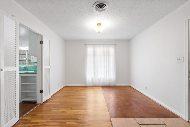 unfurnished room featuring light hardwood / wood-style flooring and a textured ceiling