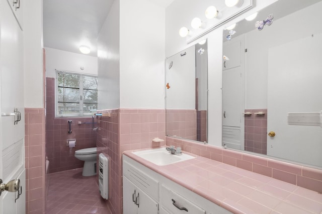 bathroom featuring tile patterned flooring, vanity, toilet, and tile walls