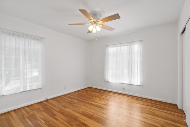 spare room with light hardwood / wood-style floors, a wealth of natural light, and ceiling fan