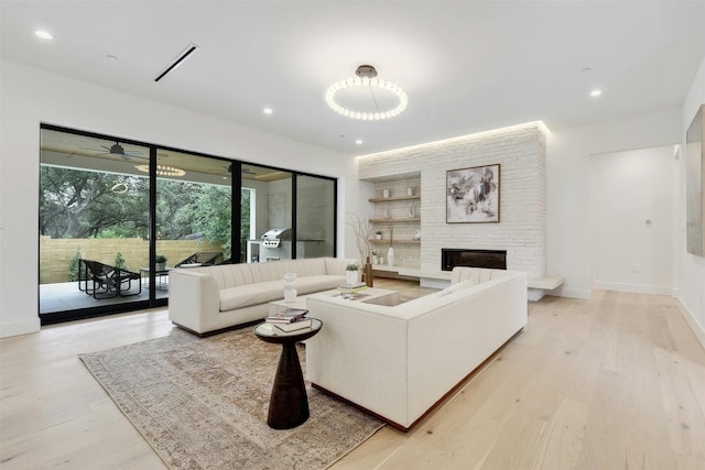 living room with ceiling fan, a fireplace, and light wood-type flooring