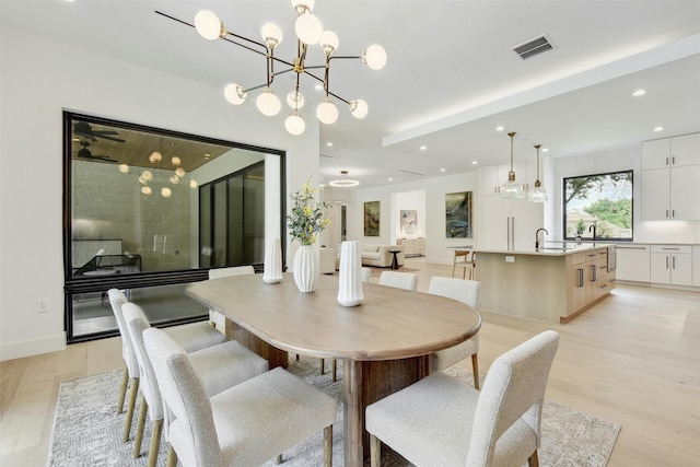 dining space featuring an inviting chandelier, sink, and light hardwood / wood-style flooring