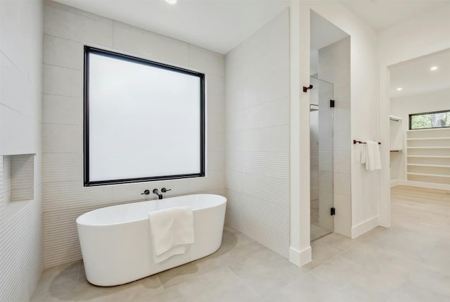 bathroom featuring plus walk in shower, tile patterned floors, and tile walls