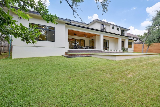 rear view of property featuring a lawn and ceiling fan