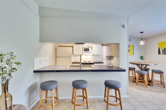 kitchen with white appliances, sink, hanging light fixtures, tasteful backsplash, and white cabinetry